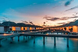 Images Dated 26th May 2019: Maldives island and water villas. Island in ocean, overwater villas at the time sunset with led