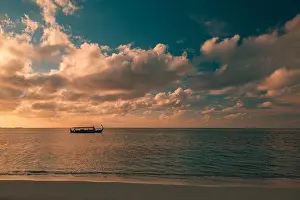 Maldives Sunset cruise with Dhoni boat in Maldives islands. Tropical sea sunset, seascape. People enjoying the sunset and looking for marine life