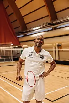 Mature Men Prints: Male badminton player standing with hand on hip while holding racket at sports court