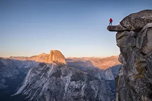 Yosemite Prints: A male hiker standing on an overhanging rock at Glacier Point enjoying the breathtaking view towards famous Half Dome