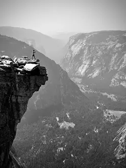 A male hiker taking a photo of the lower Yosemite Valley from the top of half dome