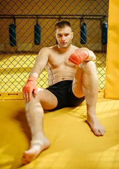Punch Prints: Male MMA fighter sitting on the floor in a cage