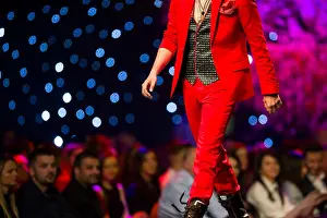Unrecognizable Prints: A male model walks the runway in modern red suit during a Fashion Show