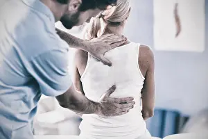 Massaging Prints: Male physiotherapist giving back massage to female patient