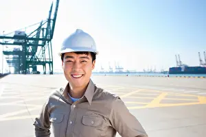 30 34 Years Prints: Male shipping industry worker with hands on hips with shipping dock background