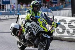 Fluorescent Prints: A male spanish civil guard on a motorcycle with a yellow uniform driving through a paved road