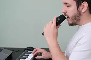 Influencer Prints: A man blogger, youtuber, influencer recording a video playing the electronic piano and singing at home