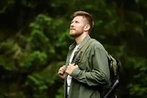 Surrounded Prints: Man carrying backpack hiking in lush forest