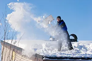 Winterly Prints: A man clears the snow off the roof of his house