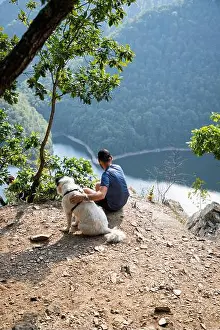 man and dog on mountain top overlooking a lake