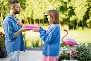 Man gives a gift in pink box to his woman, celebrating outdoors