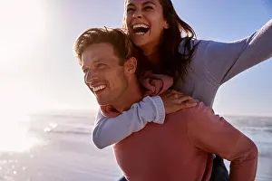 Piggyback Prints: Man Giving Woman Piggyback On Winter Beach Vacation