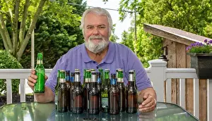 Socializing Prints: A man with a gray beard sits at a table on a sunny patio surrounded by empty bottles