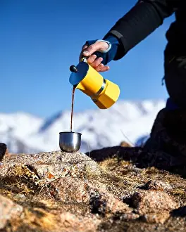 Stove Prints: Man hiker pouring coffee from Yellow Moka mocha pot outdoors in the snow winter mountains