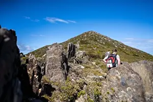 Wide Shot Prints: man hiking up a mountain with a backpack, alpine wilderness