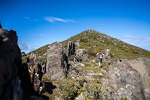 Wide Shot Prints: man hiking up a mountain with a backpack, alpine wilderness