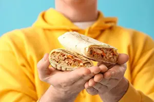 Wrapped Prints: Man holding doner kebab on blue background, closeup