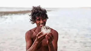 Wonders Prints: A man holds a pufferfish while standing in shallow waters off the coast of Socotra