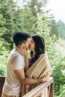 A man hugs and kisses a woman on the balcony. They have a honeymoon or close relationship and love