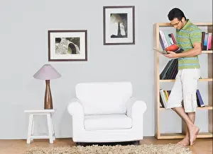 Barefoot Prints: Man leaning against a bookshelf and reading a book