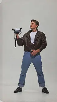 Oldschool Prints: Man in leather jacket holding vintage camcorder with confident pose