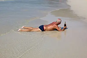 Man lying on Patpong Beach with a bottle of Beer