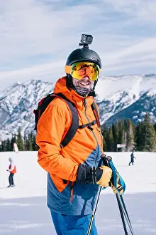 Weekend Activities Prints: A man in orange ski jacket, with a head cam and helmet