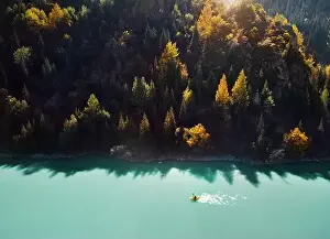 Man is paddling on yellow raft boat in the mountain lake at autumn time. Aerial Drone shot