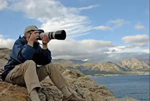Photographers Prints: Man photographer taking a photograph of a landscape with telephoto lens
