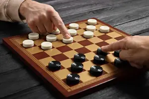 Intellect Prints: Man playing checkers with partner at black wooden table, closeup