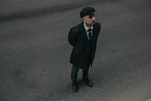 Vest Prints: A man posing in the image of an English retro gangster of the 1920s dressed in Peaky blinders style at city street