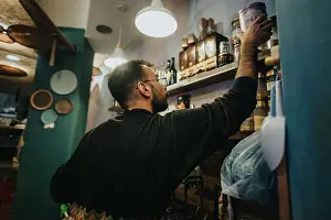 Homey Prints: Man reaching for a product on a shelf in a cozy small store