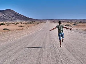 Mid Adults Prints: Man running freely on an endless road, rear view, Damaraland, Namibia