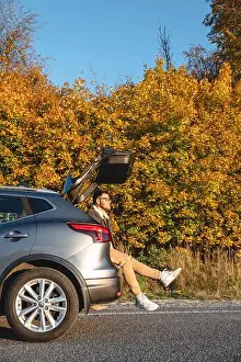 Casual Attire Prints: A man sits in the trunk of his car and enjoys the autumn sun as he basks in it