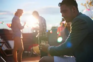 Tiredness Prints: Man sitting alone with drink at early evening party