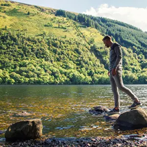 One Man Only Prints: Man standing on rocks on riverbank, Scotland, UK
