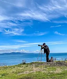 Magnification Prints: Man standing by the Salish sea with a telescope bird watching