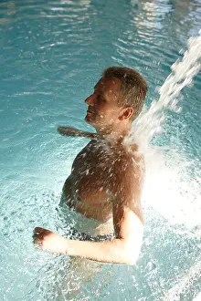 Caucasians Prints: Man in swimming pool from behind with massaging jet of water