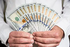 One Hundred Prints: A man uses both hands to fan out a stack of brand new one hundred dollar bills in US currency