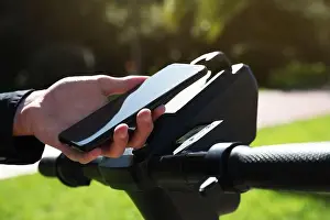 Rental Prints: Man using smartphone to pay and unblock rental electric scooter outdoors, closeup