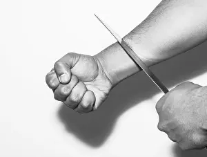 Despair Prints: Man want to commit suicide by cutting his veins with knife on white background