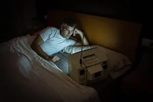Awake Prints: A man watches an old television on the bed at night in the dark. Retro TV