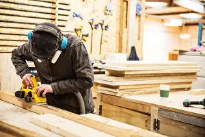 25 30 Years Prints: Man wearing ear protectors, protective goggles and dust mask standing in a warehouse