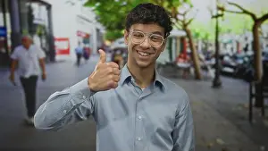 Approval Prints: Man wearing glasses and a blue shirt energetically gives thumbs up on a city street; approval confidence