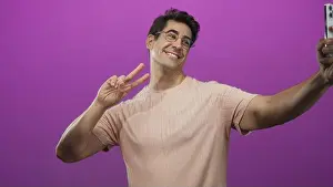 Grin Prints: Man wearing glasses and peach t shirt holds smartphone for selfie