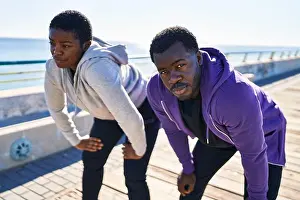 Exhausted Prints: Man and woman couple wearing sportswear tired resting with hands on knees at seaside