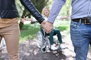 Disability Prints: Man and woman hold on to hand and walks away from woman in wheelchair