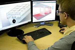 Analyzing Prints: A man working at his desk in front of dual flat screen monitors