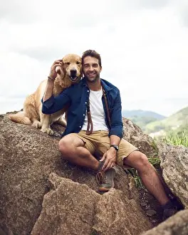 Labrador Prints: Mans best friend for life. a handsome young man sitting on a rock with his golden retriever after a day out hiking