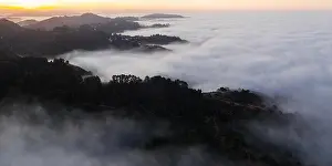 The marine layer, a moist air mass developing over the Pacific in the presence of a temperature inversion, seeps over the San Francisco Bay Area